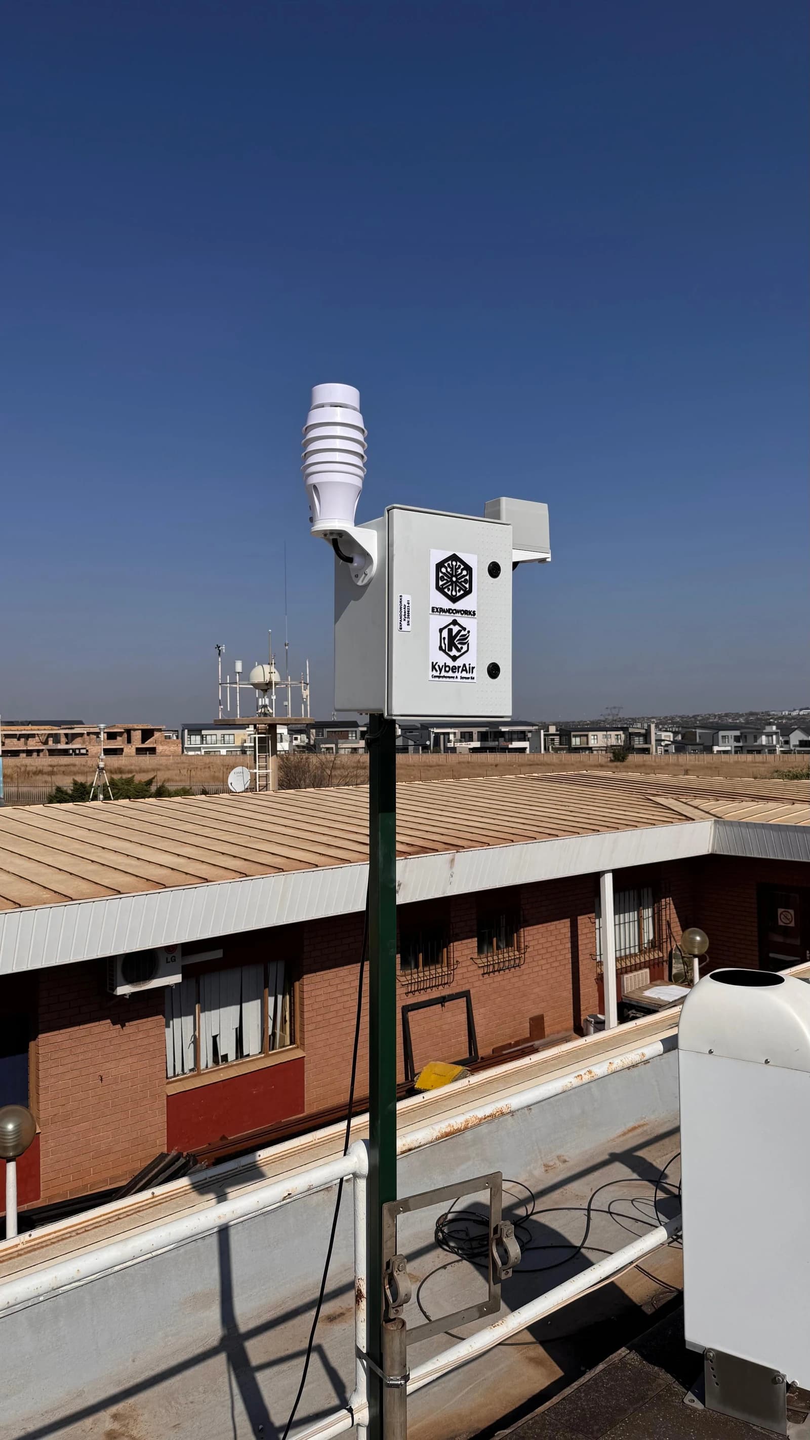 KyberAir monitoring unit installed on a metal pole above a rooftop