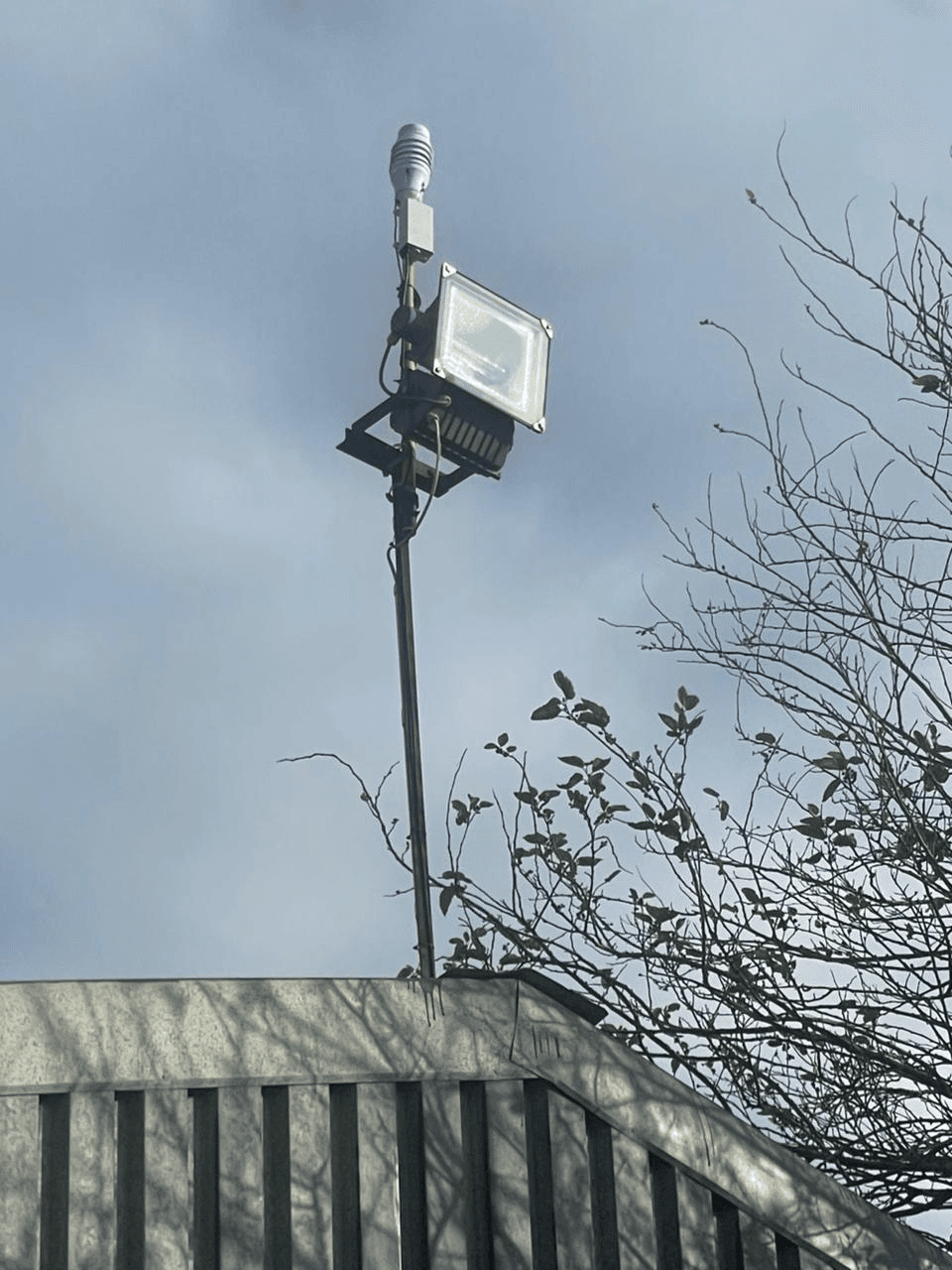 Outdoor KyberMini particulate monitoring installation with wind, light, and noise monitoring sensors mounted above a building.